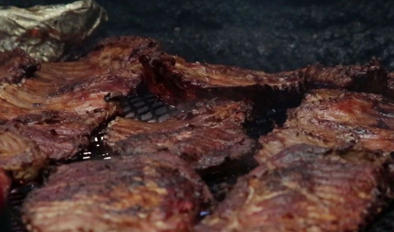 Ribs cooking on open coals in the Archibald's pit